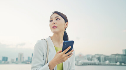 都市を背景にスマホを見る女性