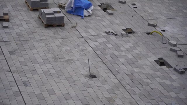 Process of construction of gray brick paved sidewalk, half built pavement road