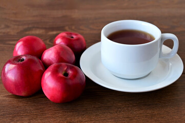 Autumn composition of red apples lying on wooden table and white cup of tea. Concept of home comfort and warmth. Hello, September!