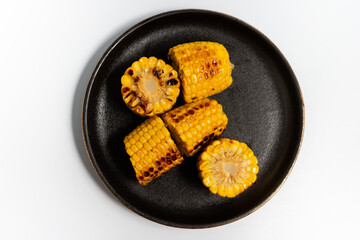 fried corn on a black plate on a white background top view 