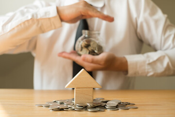 Man's hand protects glass bottles, saves money with coins, steps towards real estate Investment savings concept