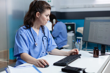 Pharmacist specialist nurse analyzing medical examination using computer in hospital office during...