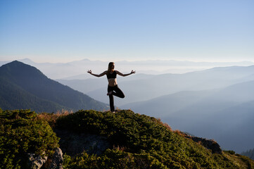 Front view of young attractive woman doing meditation on fresh air in the morning with beautiful landscape. Concept of meditation.