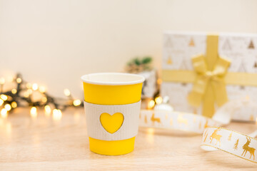 Takeaway coffee cups on gold lights background with christmas gifts