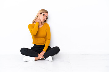 Fototapeta premium Blonde Uruguayan girl sitting on the floor with neckache
