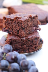 brownie cake with grapes, white background, on wooden slice