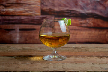 golden tequila with lemon slice in elegant glass on wooden planks