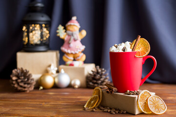 A red frosted cup with marshmallows and cinnamon on a Christmas background.