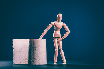 Wooden figure sit on a roll of toilet paper. Concept of the problem with digestion.