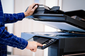 Businessmen press button on the panel for using photocopier or printer for printout and scanning document paper at office.