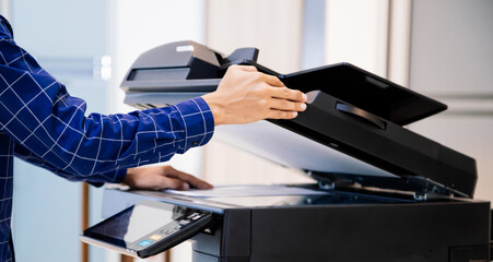 Businessmen press button on the panel for using photocopier or printer for printout and scanning document paper at office.