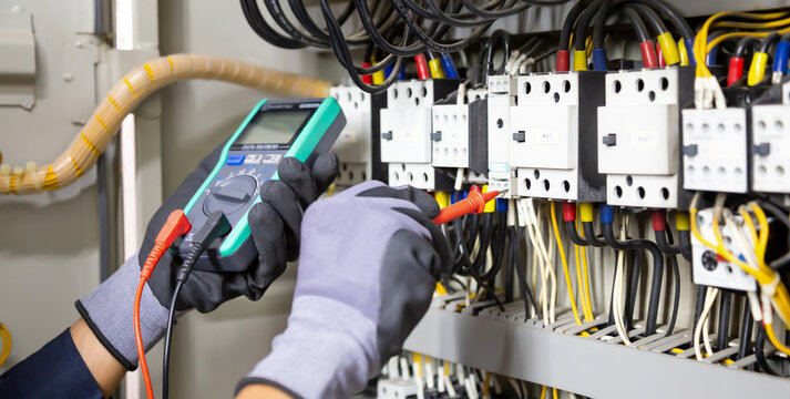 Electrician engineer tests electrical installations and wires on relay protection system. Adjustment of scheme of automation and control of electrical equipment.