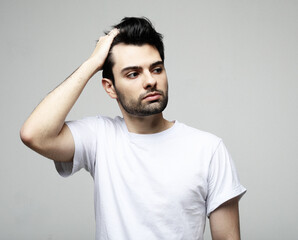 Fototapeta premium Handsome young brunette man in smart casual wear looking at camera, over white background