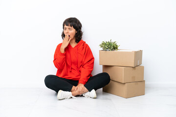 Young girl moving in new home among boxes isolated on white background yawning and covering wide open mouth with hand