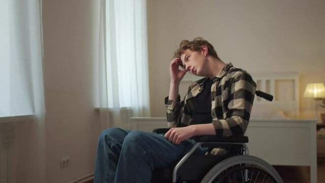 A young disabled man is riding in his wheelchair around the room