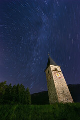 church bell tower at night with star trails in the night sky
