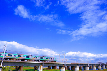 青空を背景に河を渡る列車