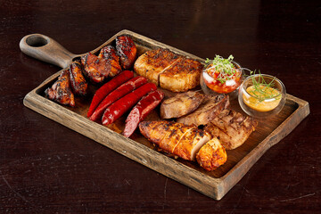 assortment grilled sausages, chicken, meat with vegetables on wooden background