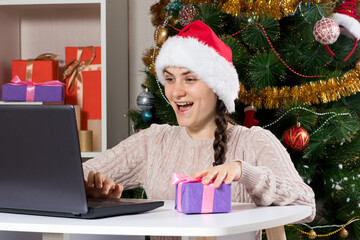 A woman in a Santa Claus hat rejoices in winter Christmas discounts in online stores