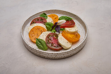 Close up caprese salad with red and yellow tomatoes, fresh basil and mozzarella cheese 