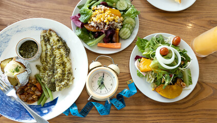 Flay lay of alarm clock of Intermittent fasting as healthy food and meal plan, weight loss concept on wooden table background