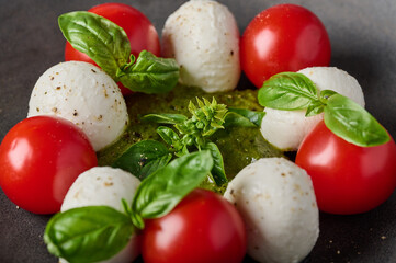 Macro view italian caprese salad with tomatoes, pesto, basil and mozzarella cheese, selective focus