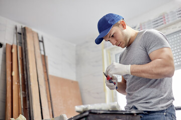 Young adult man painting and fixing on a DIY budget renovation of his new home apartment.