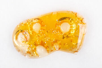 spreading drop of gold cannabis concentrate, wax with a high content of THC isolate