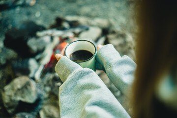 cup with coffee in female hands in nature