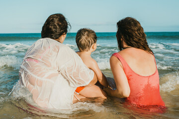 Unrecognizable mothers with son admiring waving sea in summer