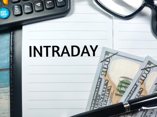 Pen,banknotes,calculator and glasess with word INTRADAY written on notebook.Business concept.