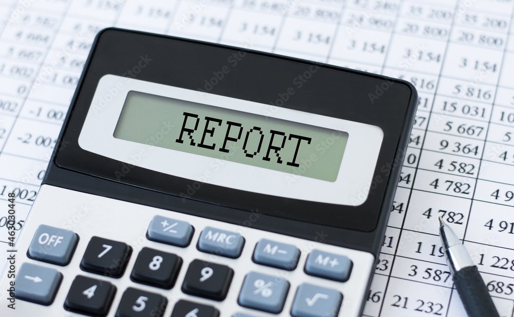 Poster report text in the calculator screen on the office desk with a pen and financial statements
