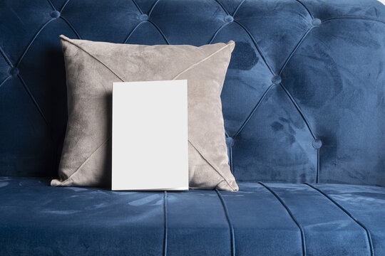 Book With The Blank White Cover Against A Velvet Square Cushion On A Blue Sofa Mockup