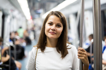 Portrait of young female passenger standing in subway car