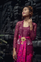 Beautiful Asian girl dressed in traditional Balinese kebaya costume outside a Hindu temple, styles Bali, Indonesia.