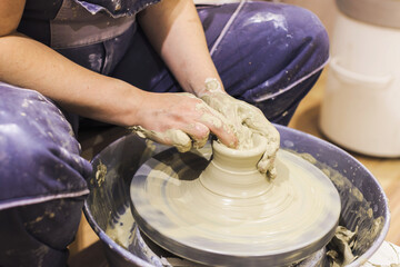 Female pottery artist working with clay on pottery wheel at ceramic art workshop