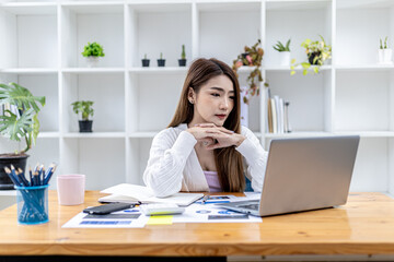 Fototapeta na wymiar Beautiful Asian young woman looking at information on a laptop, concept image of Asian business woman working smart, modern female executive, startup business woman, business leader woman.