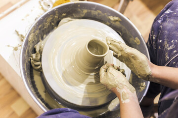 Female pottery artist working with clay on pottery wheel at ceramic art workshop