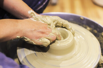 Pottery artist, female hands mold clay on pottery wheel at ceramic art workshop