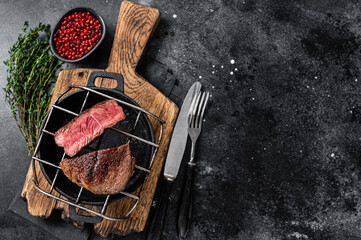 Beef tenderloin steak is grilled on a grill pan. Black background. Top view. Copy space