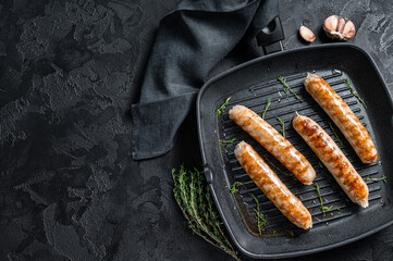 German grilled Bratwurst sausages in a grill pan. Black background. Top view. Copy space