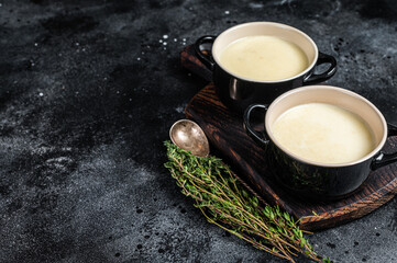 Obraz na płótnie Canvas Potato cream soup in bowls on kitchen table. Black background. Top view. Copy space