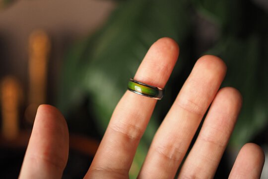 Green Mood Ring Detail On The Index Finger Of An Open Hand