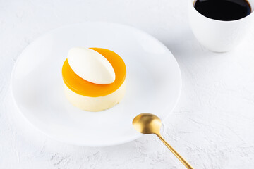 Mousse cake with mango and passionfruit on a white plate.