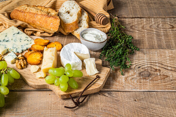 Fototapeta na wymiar Assorted Cheese Brie, Camembert, Roquefort, parmesan, blue cream cheese with grape, fig, bread and nuts. wooden background. Top view. Copy space