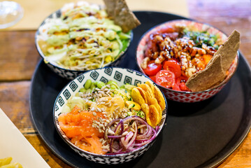 Bowls with various vegetables and seeds with fish on tray