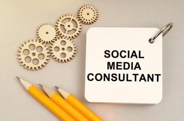 On the table are gears, pencils and a notebook with the inscription - Social Media Consultant