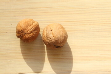 Walnut on a light wood background. Walnut is the fruit of a tree that can reach a height of 25 meters and live up to 400 years. 