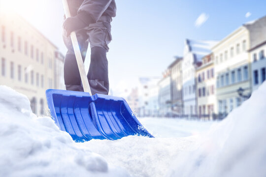 Person using a snow shovel on a street in winter
