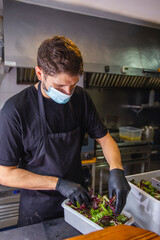 cook preparing food with safety and hygiene measures in a restaurant kitchen